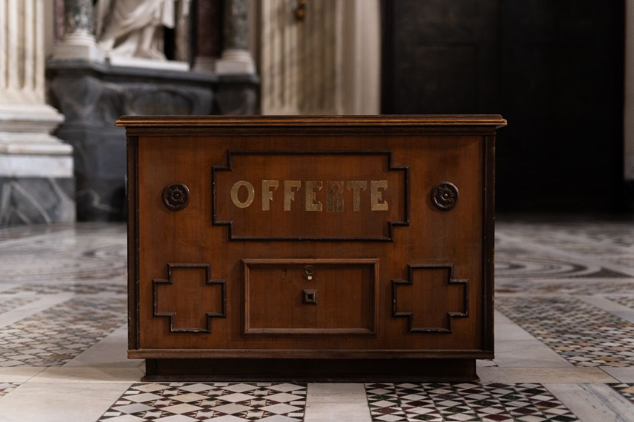 cta-img-01 A vintage wooden offertory box in an Italian church interior, highlighting intricate design.