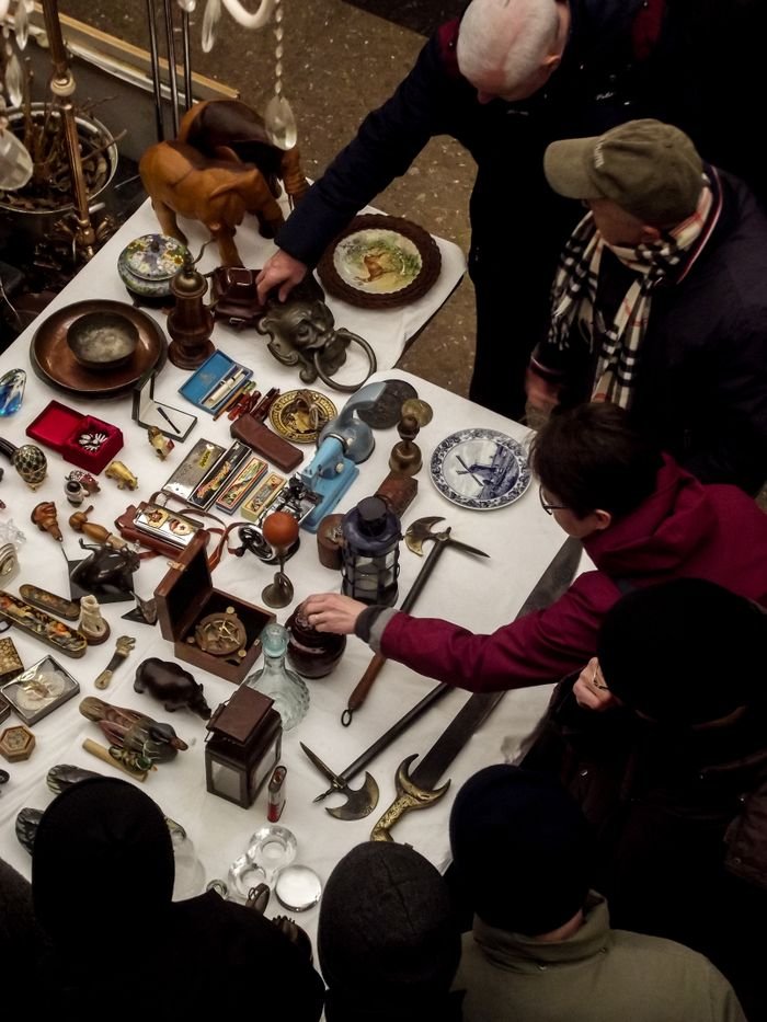 gallery-06 Group of people inspecting vintage antiques and collectibles at a bustling flea market.