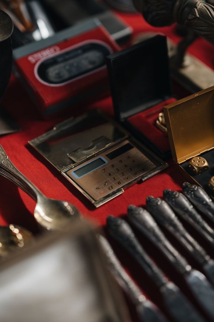 classes-01 A close-up of retro calculators and cutlery on a red table, exuding a vintage aesthetic.