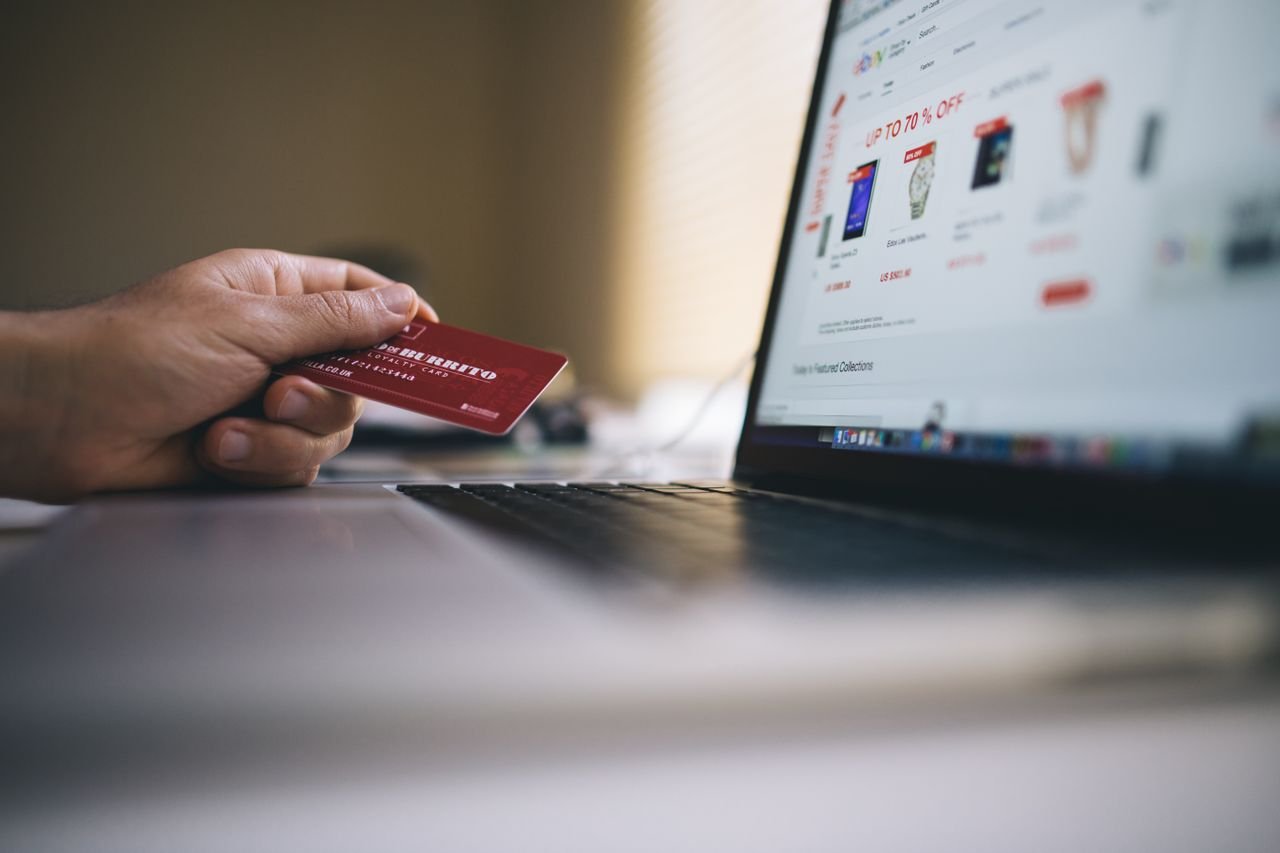 gallery-7 Person holding a credit card while shopping online on a laptop, indicating ecommerce transactions.